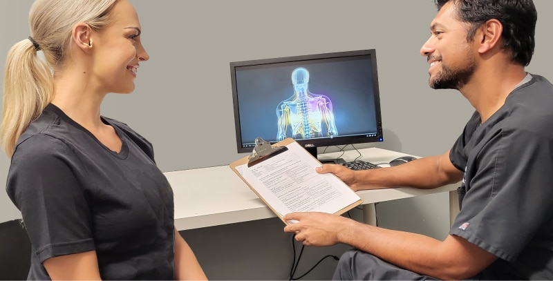 Chiropractor Talking to Patient with Clipboard